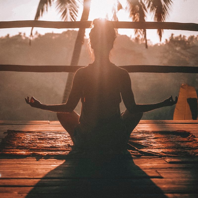 A figure meditating in silhouette against the morning light